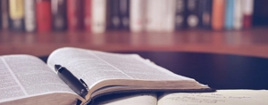 Biblie deschisă cu un stilou, simbolizând studiul poruncilor lui Dumnezeu.